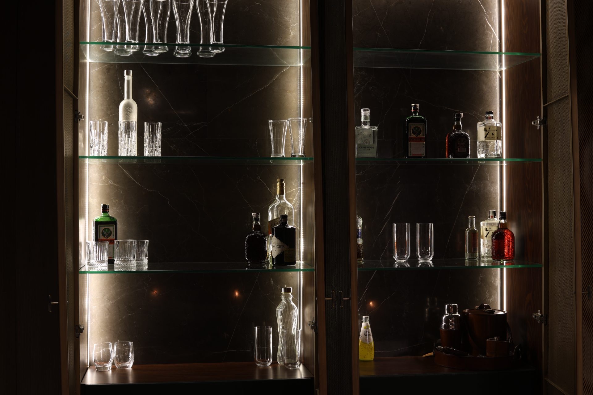 Back-lit bar cabinet — glass shelves against dark marble