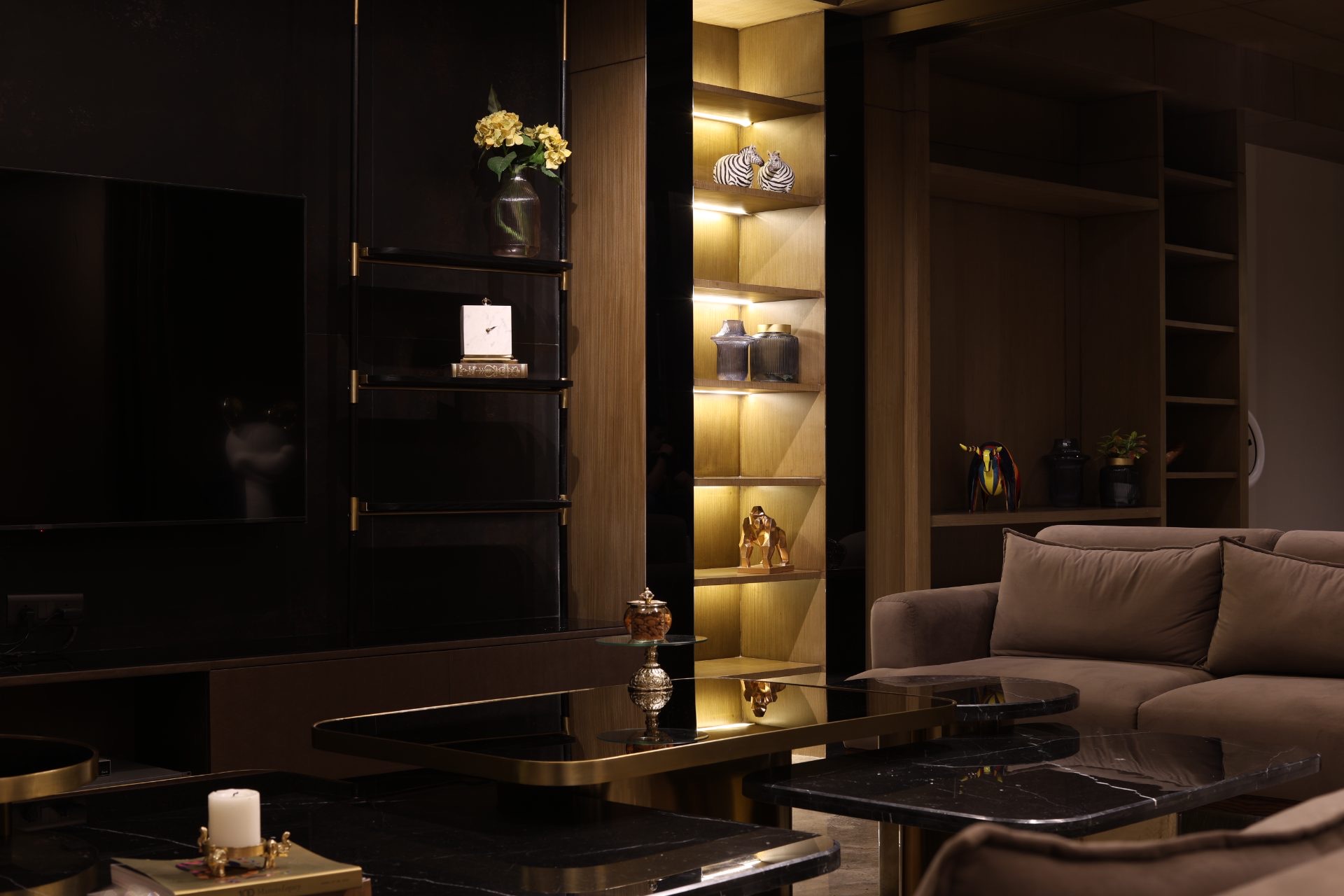 Living room at night — lit oak niches, brass and black marble